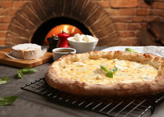Delicious hot cheese pizza and ingredients on grey table against oven