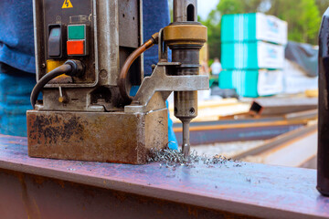 Steel beams are drilled with precision at construction site showcasing machinery in use.