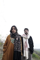 A couple posing in traditional Kashmiri attire, adorned in handwoven shawls and embroidered pherans, showcasing the rich heritage and artistry of Kaar Kash in a styled fashion shoot.

