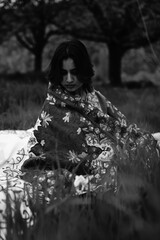 Girl wrapped in a luxurious silk carpet, seated on an intricately embroidered sheet laid over...