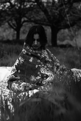 Girl wrapped in a luxurious silk carpet, seated on an intricately embroidered sheet laid over...
