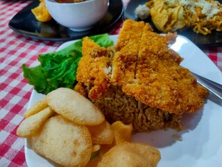 Fried rice with chicken katsu on a white plate.