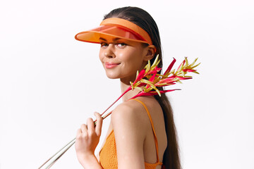 Stylish young woman with a vibrant visor and tropical flowers against a bright white background, exuding confidence and summer vibes.