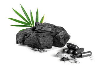 Natural wood charcoal with charcoal capsules and bamboo leaves isolated on white background.