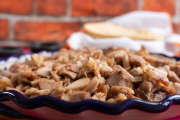 Pork carnitas dish, taco meat in Mexico, on a large plate and table, ready to eat