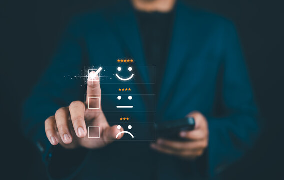 Businessman selecting happy face icon on virtual screen for rating service experience using futuristic interface. Customer satisfaction and digital feedback concept.