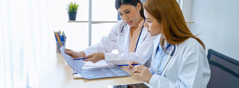Fototapeta Banner hands of two women doctor medical lab discussing together healthcare teamwork. Panorama Two asian women doctors meeting write prescription medical clinic office using laptop with copy space.