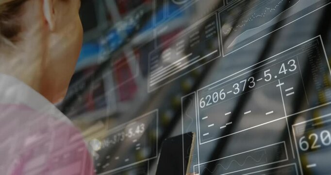 Woman boarding escalator and tapping smartphone while monitoring tech data panels in transit hub