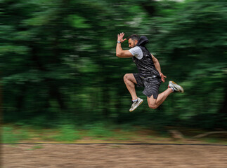 Man running and jumping in the park or forest running trail, with added motion blur 