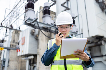 Engineer is working at high voltage power substation conducting inspection and check of...