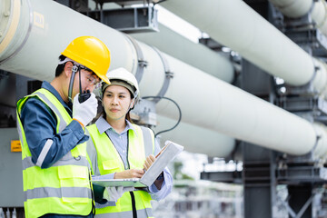 Engineer is working at high voltage power substation performing inspection and check of infrastructure to ensure safety and proper operation of equipment
