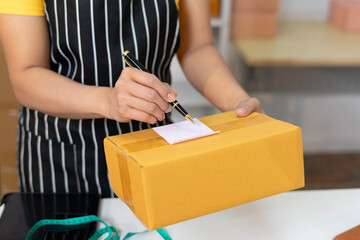 Person writing on package with pen, preparing for shipment