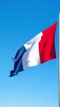A vibrant French flag billows against a bright blue sky a perfect Bastille Day vertical video capturing the patriotic spirit from a low angle view.