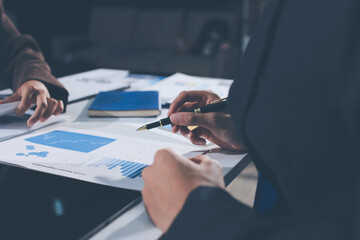 Focused young businessman signing agreement with skilled lawyer in eyeglasses. Concentrated financial advisor showing place for signature on paper contract document to male client at meeting in office