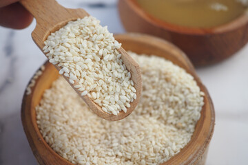 White sesame seeds being scooped from wooden bowl