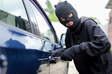 Man Dressed in Black Holding Screwdriver to Break Lock and Steal a Vehicle on The Road