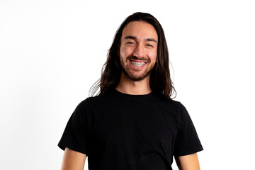 Young man makes big smile with braces, looking at camera, in studio with white background