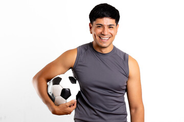 Young Latin man looks at camera and holds a soccer ball in a white background