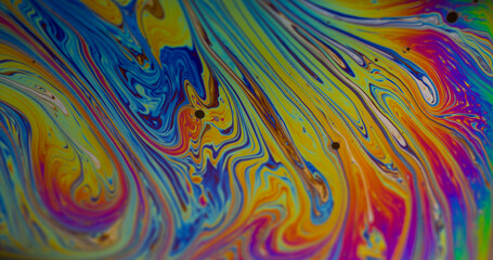 Colorful fluid. Gasoline texture. Defocused blue yellow purple bright ink liquid spilling on abstract creative acrylic art background.