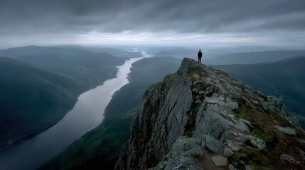 A solitary figure stands atop a jagged mountain ridge, overlooking a winding river valley.