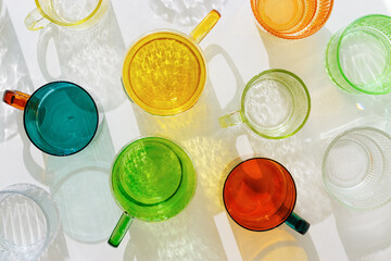 Colored Glasses pattern with shadow and sunlight reflection on white background, minimal aesthetic top view summer still life, refraction at shine drink, caustic effect, orange blue glass cups
