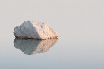 Naklejka premium minimalist photograph of single stone at edge of reservoir in germany featuring long shadows and natural symmetry