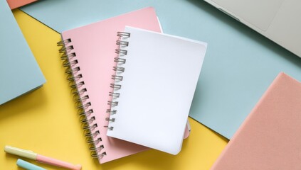Pastel-colored notebooks, blank pages, and stationery on a colorful surface