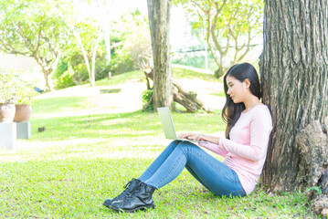 Obraz premium Lifestyle person Woman listening music and reading a book and play laptop on the grass field of the nature park in the morning . Concept lifestyle