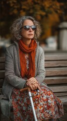 In a metropolitan park, a woman with visual impairments sits with a white cane.