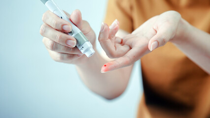 Person using blood glucose meter, checking blood sugar level by pricking finger, diabetes management, healthcare and medical concept