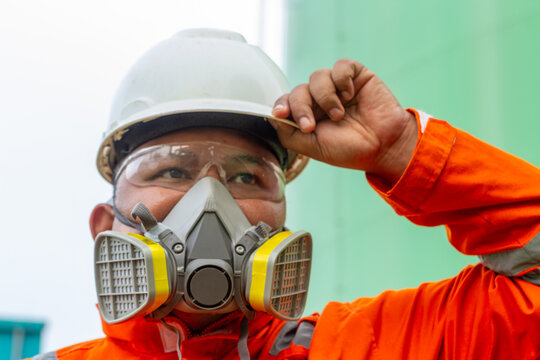 Construction worker wearing respirator, hard hat & safety glasses. Industrial safety, PPE, construction, health protection.