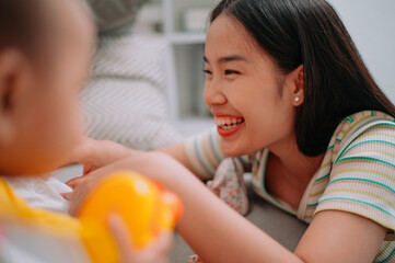 Selective focus shot, Single mother spends happy time with her twin daughters in a warm room at home. Take care of baby with love and care.