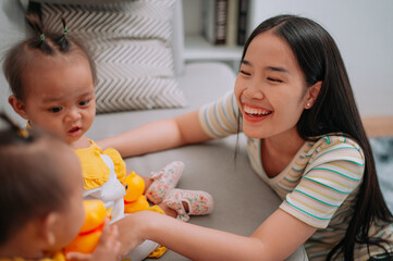 Selective focus shot, Single mother spends happy time with her twin daughters in a warm room at home. Take care of baby with love and care.
