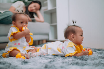 Portrait of Toddler twin girls play with toys on a soft carpet in living room at home.