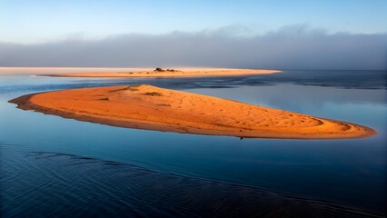 Fototapeta premium Serene sunrise over a tranquil coastal landscape featuring a small orange sand island in calm blue waters a picturesque scene of nature's beauty ideal for travel and nature photography
