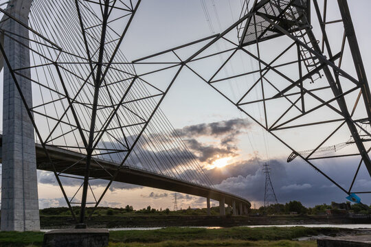 Dramatic sunrise view of Flintshire Bridge in North Wales, captured through the angular framework of an electricity pylon