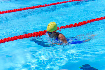 Swimmer child swims breaststroke swimming style in a race swimming pool. Water sports and competition, learning to swim classes for children.
