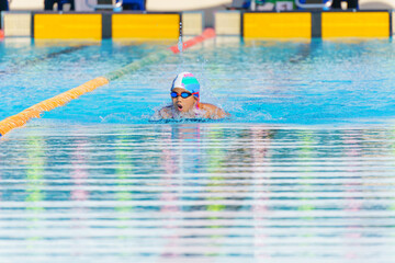Swimmer child swims butterfly swimming style in a race swimming pool. Water sports and competition, learning to swim classes for children.