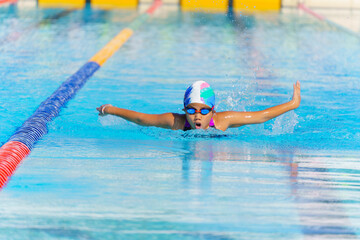 Swimmer child swims butterfly swimming style in a race swimming pool. Water sports and competition,...