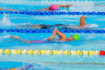 Swimmer child swims freestyle swimming style in a race swimming pool. Water sports and competition,...