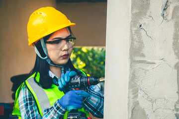 Female worker is using a drill to drill a pole.