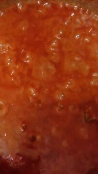 Boiling tomatoes stew with steam coming off while cooking. Tomatoes stew made with onion, tomato, pepper, ginger, garlic and oil. Preparing red stew.