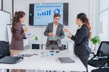 Group of Asian business people standing in a meeting, with tablets and iPads on the table, planning...