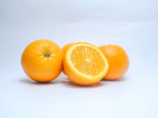 Orange fruits pile on white background, beautiful skin, delicious. There are halved and unhalved fruits. High vitamin C fruit concept.