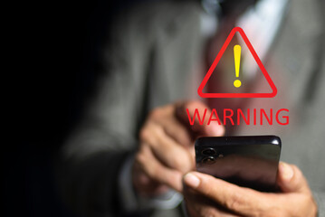 Businessman using smartphone with triangle caution warning sign for notification error and maintenance concept. Emergency warning alert alarm on Smartphone, Data network protection, Virus alarm.