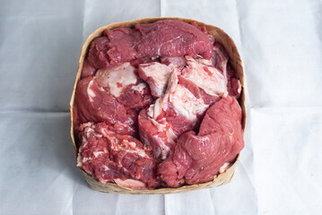 Fresh Raw Meat Cuts in Woven Basket on White Paper Background