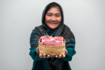 Smiling woman presents woven basket brimming with fresh raw meat