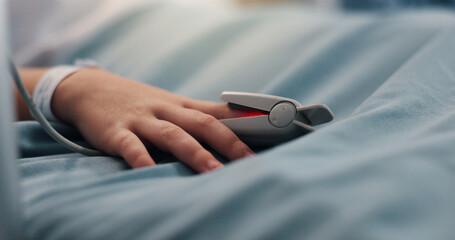 Hand, child and pulse oximeter on hospital bed to measure blood levels, monitor and recovery. Closeup, young patient and resting with medical machine, track oxygen and critical care from procedure