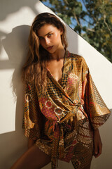 Sensual portrait of a young woman sitting on geometric stairs in a delicate lace mini dress. Soft...