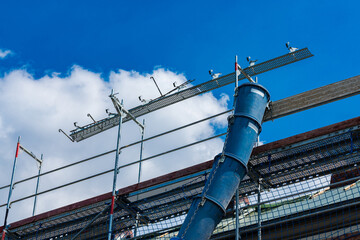 Construction site with scaffolding and concrete chute against blue sky